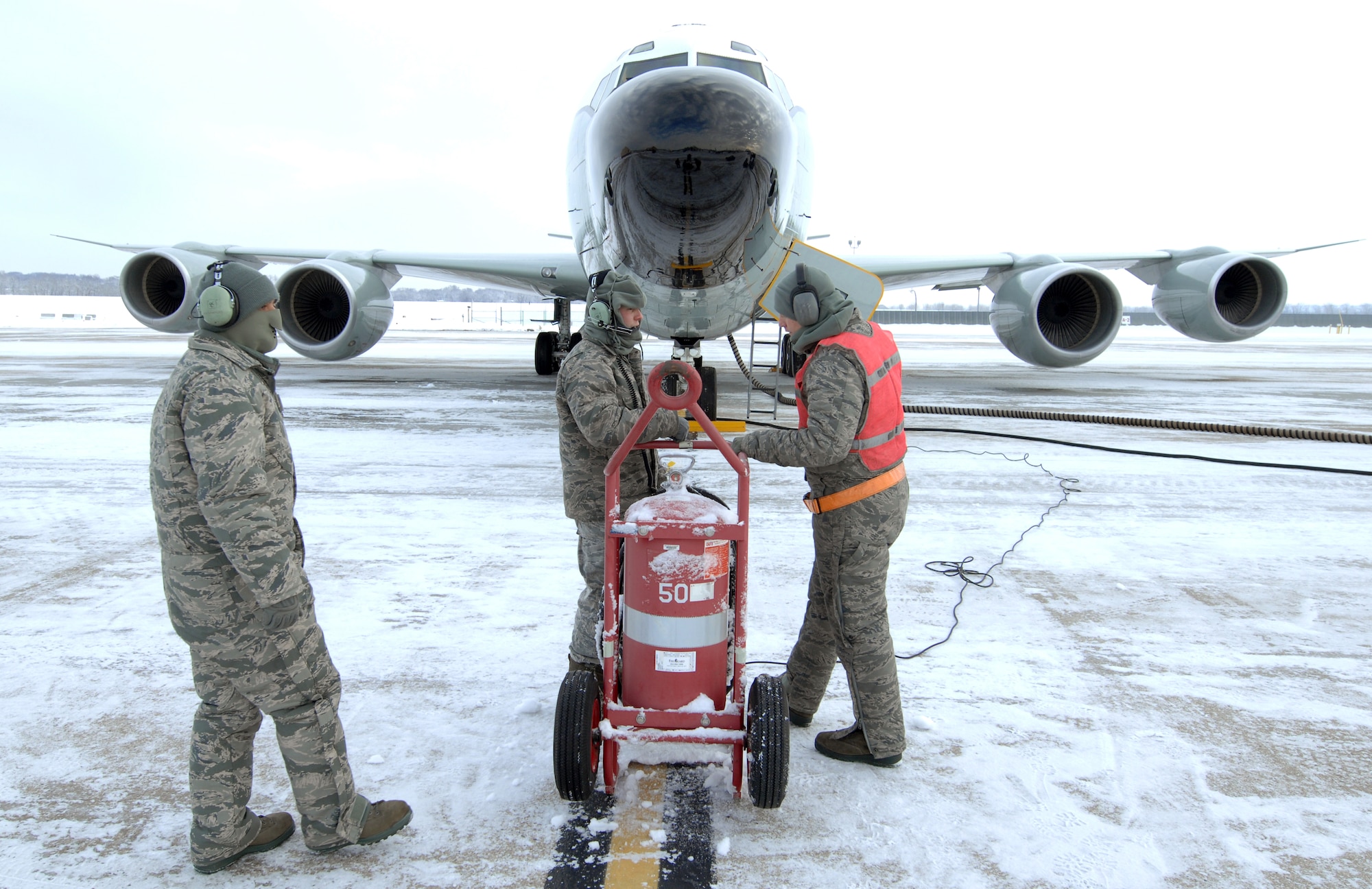 U.S. Air Force Staff Sgt. Vincent Vasquez, left, U.S. Air Force Airman 1st Class Jordan Scott and Senior Airman Jacob Bryson, right, standby while preparing an RC-135 Rivet Joint for launch Feb. 3 at Offutt Air Force Base Neb. Additional maintenance time is typically needed during winter operations to heat aircraft and to remove snow and ice from the aircraft prior to take-off.  They are all crew chiefs assigned to the 83rd Aircraft Maintenance Unit, 55 Aircraft Maintenance Squadron. (U.S. Air Force photo by Delanie Stafford/Released)