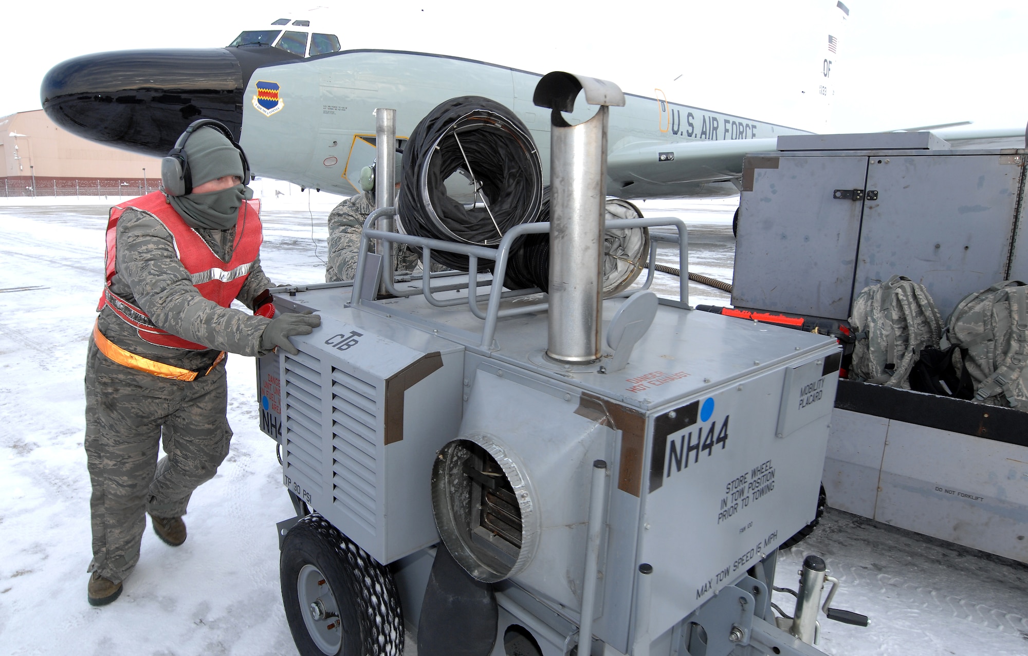 U.S. Air Force Senior Airman Jacob Bryson and another airman push a heater cart out of the path of an RC-135 Rivet Joint while preparing the aircraft for launch Feb. 3 at Offutt Air Force Base Neb. Additional maintenance time is typically needed during winter operations to heat aircraft and to remove snow and ice from the aircraft prior to take-off.   Bryson is a crew chief assigned to the 83rd Aircraft Maintenance Unit, 55 Aircraft Maintenance Squadron. (U.S. Air Force photo by Delanie Stafford/Released)