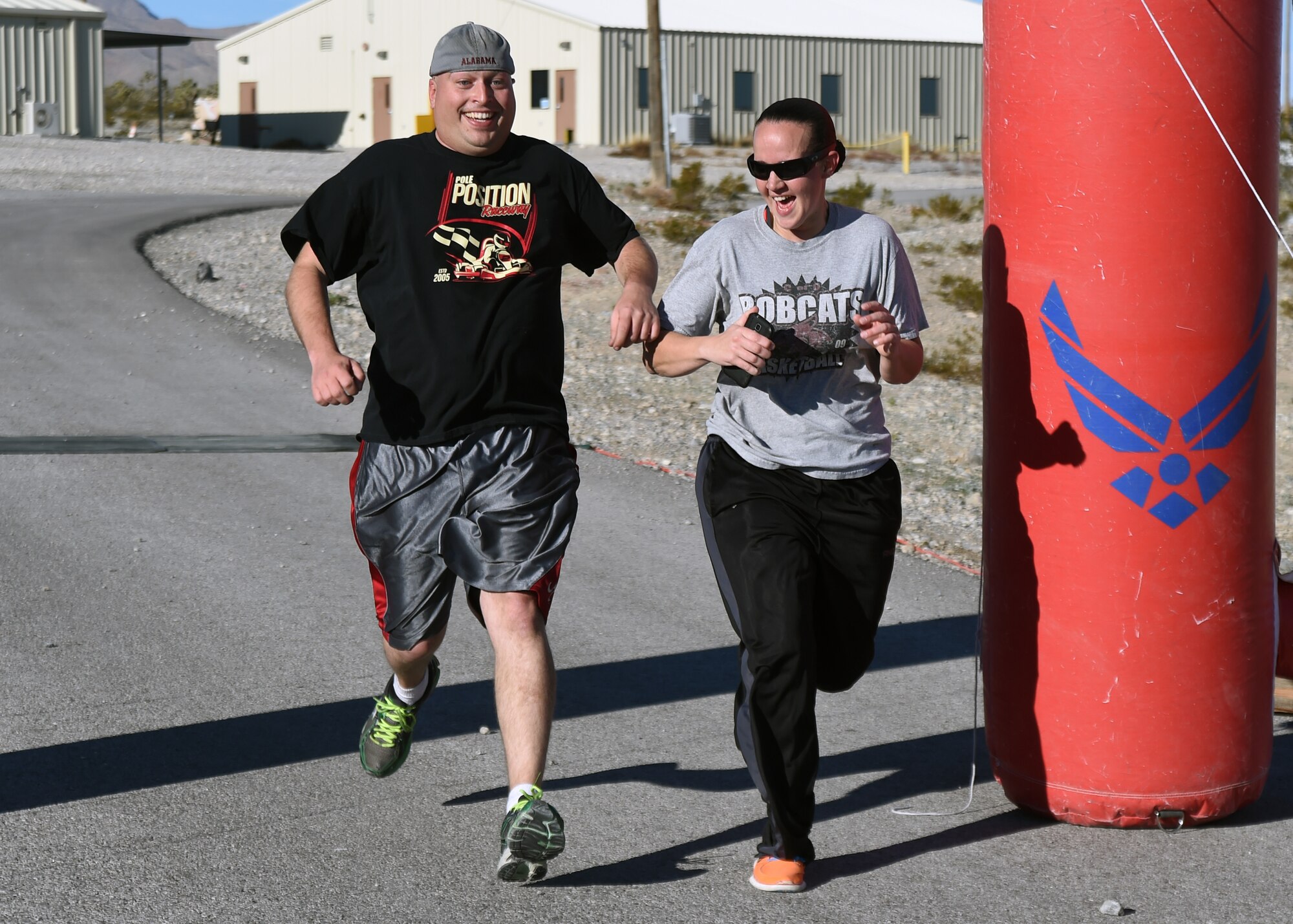99th Ground Combat Training Squadron combat arms training and maintenance instructors, Staff Sgts. David Dudley, left, and Catherine Nelson, right, race each other to the finish line during a 5K run Feb. 4, 2014 at Silver Flag Alpha training range. The 5K was one of several events held this week as part of the 99th GCTS’s draw-down and eventual inactivation, which is slated for March 2015. (U.S. Air Force Photo/Tech. Sgt. Shad Eidson/Released)


