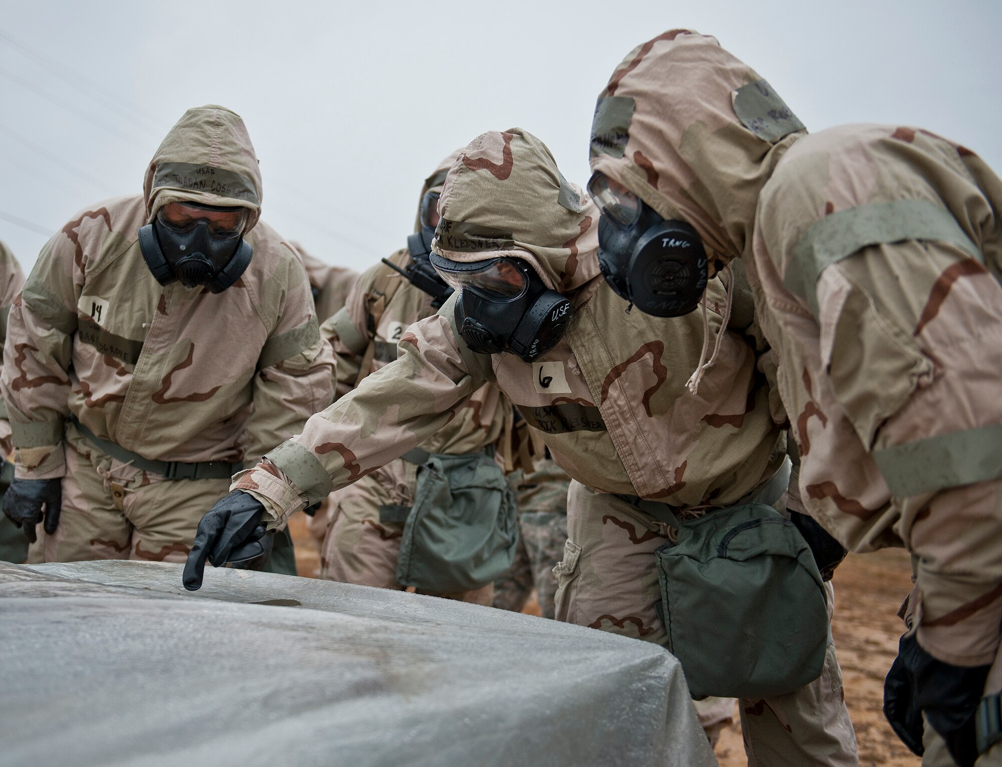 A team of Airmen assess the M8 contamination paper attached to a critical asset during a rainy Phase II readiness exercise Feb. 4 at Eglin Air Force Base, Fla.  A Phase II evaluates an Airman’s ability to meet wartime and contingency taskings of employing and sustaining the force and the ability to survive and operate. More than 30 potential deployers received classroom and practical field training during the exercise. (U.S. Air Force photo/Ilka Cole)