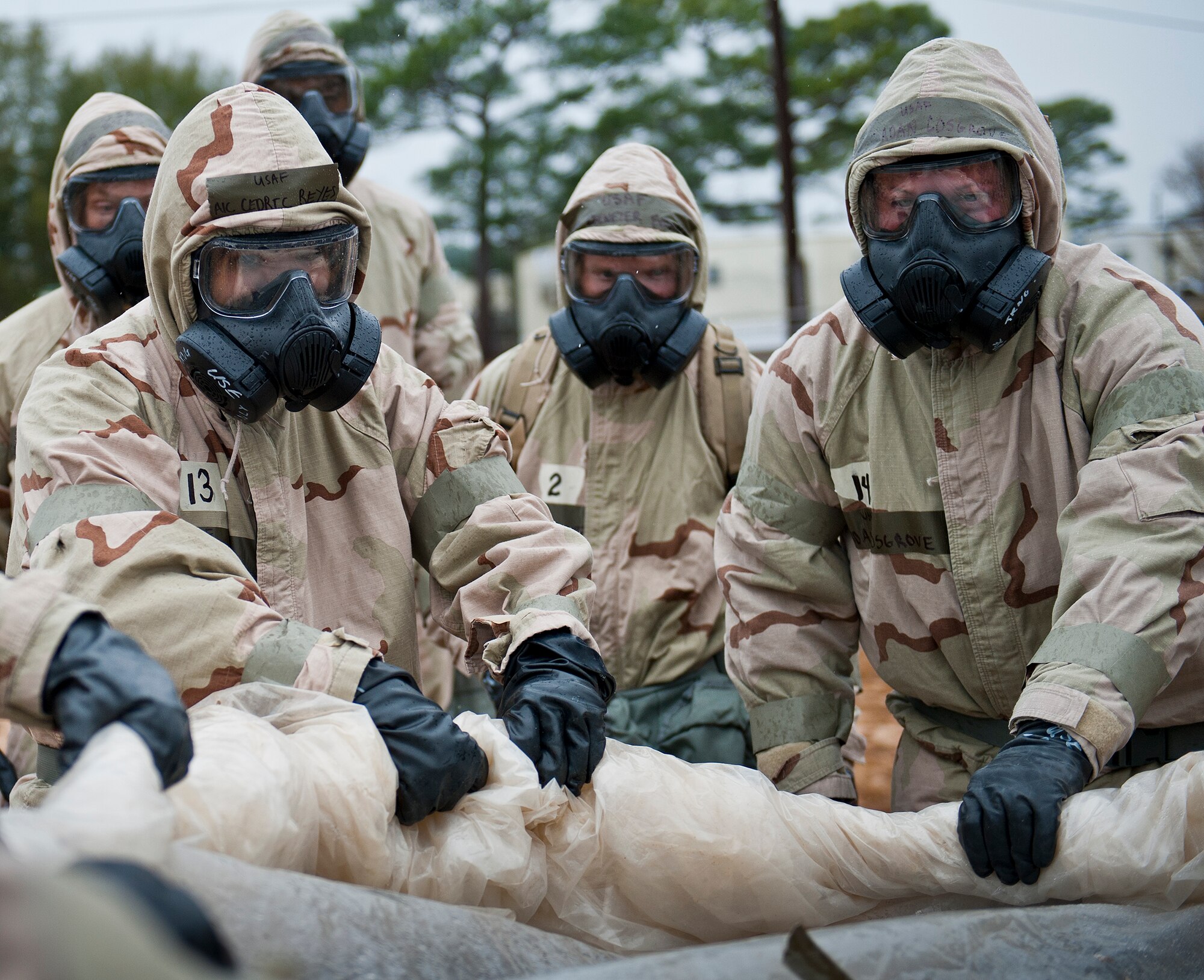 Airmen unroll a protective covering used to safeguard a critical asset during a rainy Phase II readiness exercise Feb. 4 at Eglin Air Force Base, Fla.  A Phase II evaluates an Airman’s ability to meet wartime and contingency taskings of employing and sustaining the force and the ability to survive and operate. More than 30 potential deployers received classroom and practical field training during the exercise. (U.S. Air Force photo/Ilka Cole)