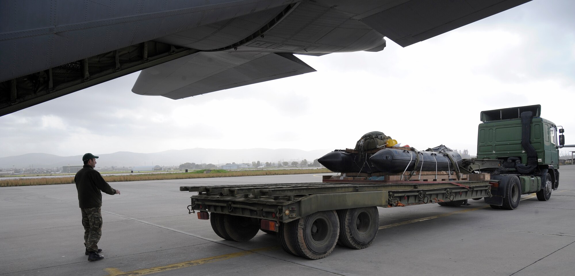 A Hellenic air force Airman guides a truck into position to load a Greek-configured boat rig onto a C-130J Super Hercules assigned to the 37th AS in Elefsis, Greece, Feb. 6, 2015. The rig was prepared to be dropped from the C-130 during Stolen Cerberus II, a flying training deployment designed to gauge the capabilities of personnel and aircraft as well as increase the interoperability between the U.S. and one of its NATO allies. (U.S. Air Force photo/Senior Airman Timothy Moore)