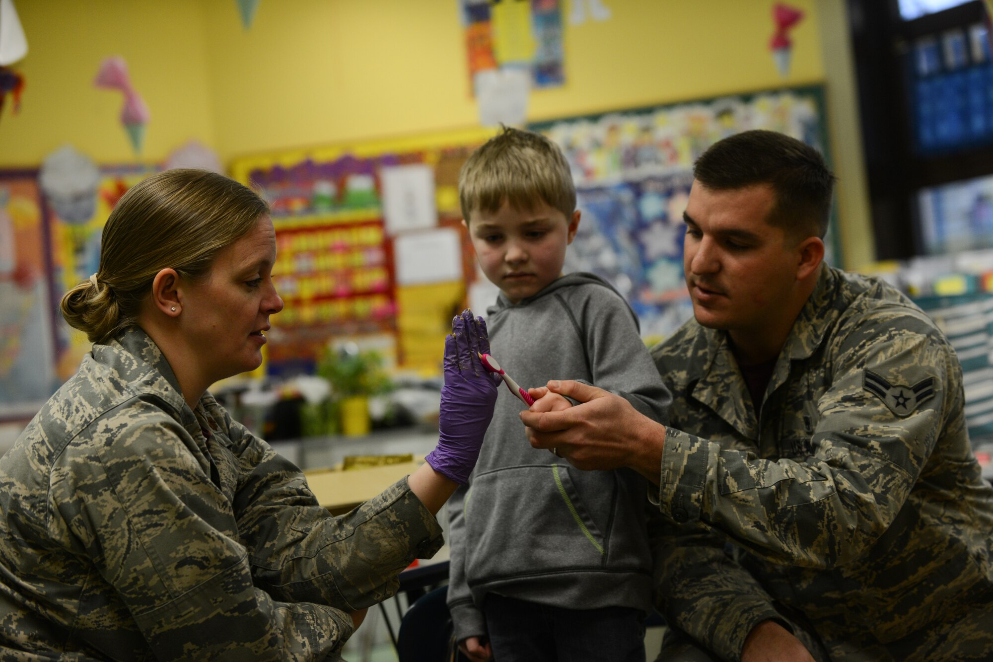 Maj. Audra Myers and Airman 1st Class Drake Futch, 86th Dental Squadron dentist and dental assistant, teach a Ramstein Elementary School student how to floss during a dental hygiene presentation at Ramstein Air Base, Germany, Feb.  6, 2014. Myers and Futch, along with other Airmen from the 86th Dental Squadron visited all of the classrooms to talk to students about the importance of healthy eating and oral healthcare. (U.S. Air Force photo/Senior Airman Nicole Sikorski)