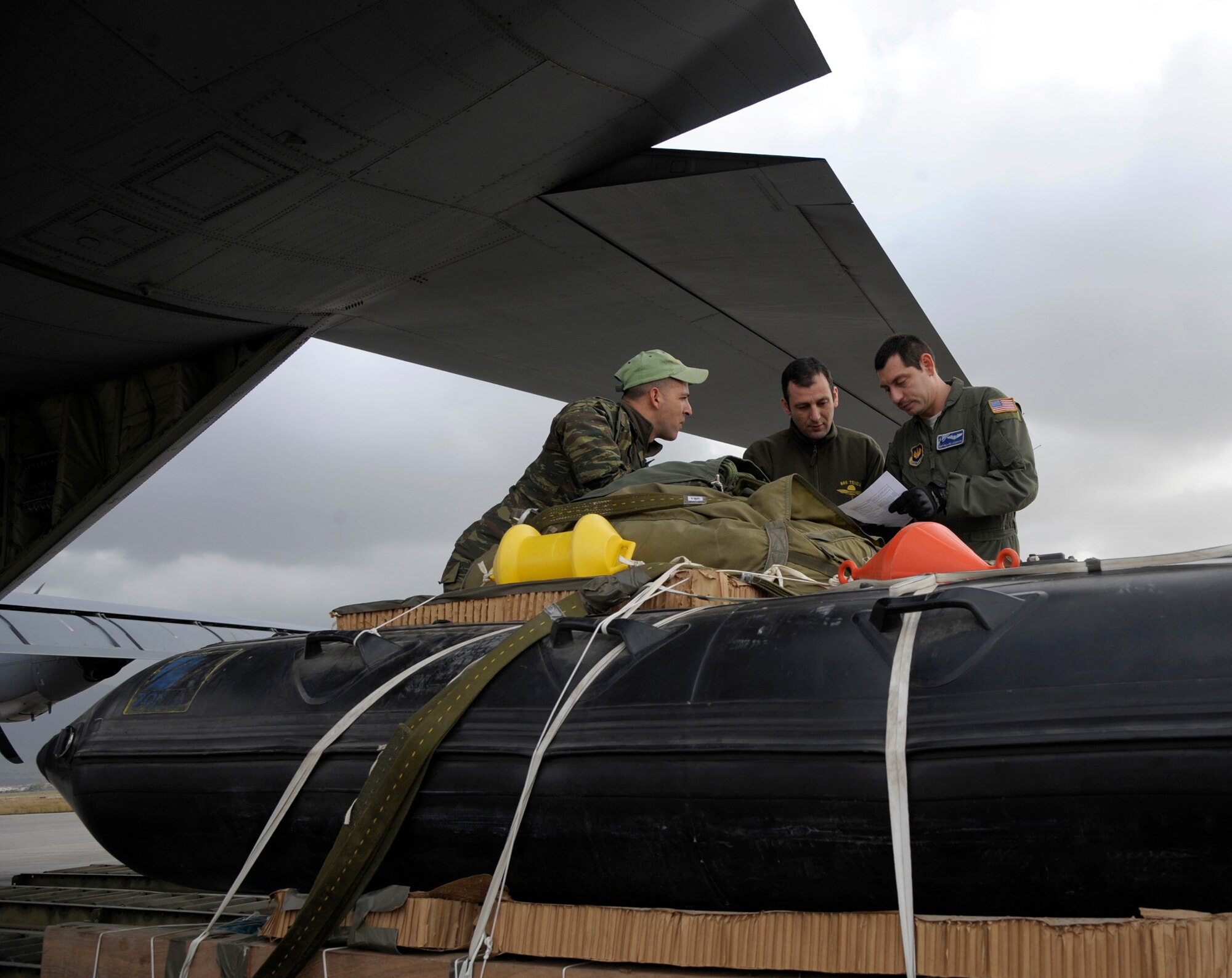 Staff Sgt. Richard Anderson, 37th Airlift Squadron loadmaster, speaks with two Hellenic air force Airmen about a Greek-configured boat rig before it is loaded onto a C-130J Super Hercules assigned to the 37th AS in Elefsis, Greece, Feb. 6, 2015. The rig was prepared to be dropped from the C-130 during Stolen Cerberus II, a flying training deployment designed to gauge the capabilities of personnel and aircraft as well as increase the interoperability between the U.S. and one of its NATO allies. (U.S. Air Force photo/Senior Airman Timothy Moore)