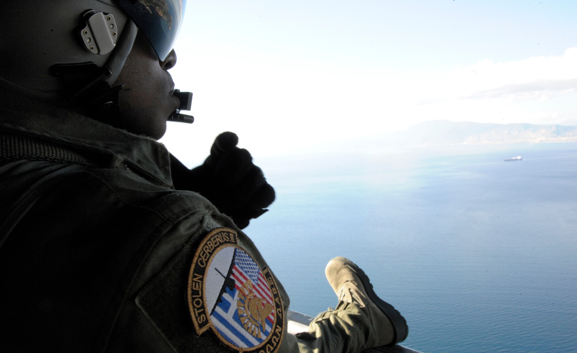 Senior Airman Ralph Colas, 37th Airlift Squadron loadmaster, looks out the back of a C-130J Super Hercules as it flies over the Greek landscape during Stolen Cerberus II, a flying training deployment, in Elefsis, Greece, Feb. 3, 2015. The FTD is designed to gauge both aircraft and personnel capabilities as well as improve the interoperability of the Airmen and their Greek counterparts. (U.S. Air Force photo/Senior Airman Nicholas Crisp)