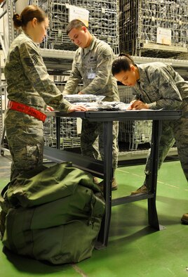 From left, Tech. Sgt. Kim Vaught, 446th Aircraft Maintenance Squadron crew chief, prepares for a mock deployment while Senior Airman Brandon Seeley and Senior Airman Sara Holt, both materiel management journeymen, issue chemical protective boots at the logistics readiness warehouse Feb. 7, 2015. Holt is from the 446th Logistics Readiness Flight, and Seeley is from the 627th Logistics Readiness Squadron. (U.S. Air Force Reserve photo by Master Sgt. Minnette Mason)