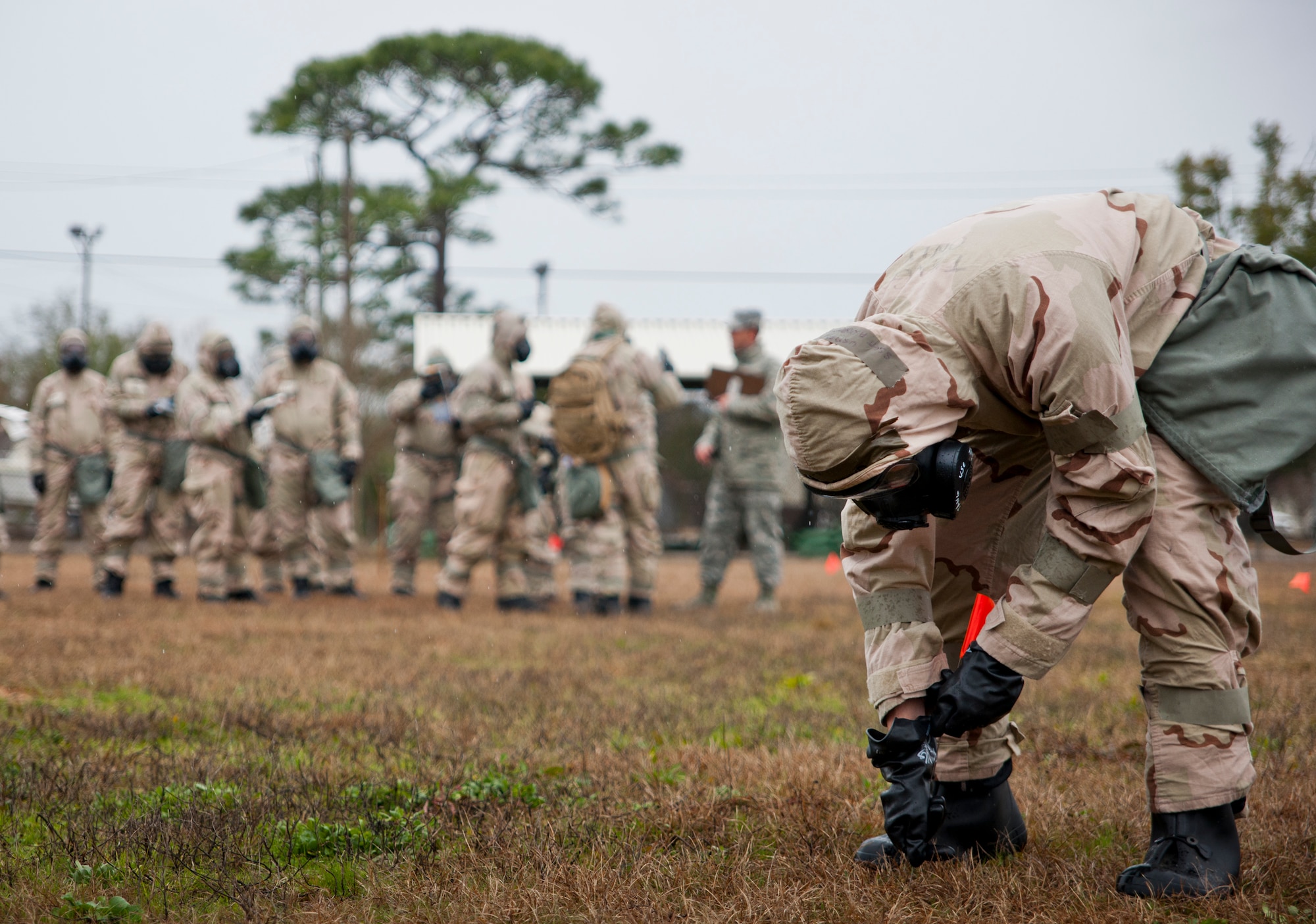 An Airman places a flag to mark off the area around a simulated unexploded ordnance during a rainy Phase II readiness exercise Feb. 4 at Eglin Air Force Base, Fla.  A Phase II evaluates an Airman’s ability to meet wartime and contingency taskings of employing and sustaining the force and the ability to survive and operate. More than 30 potential deployers received classroom and practical field training during the exercise. (U.S. Air Force photo/Samuel King Jr.)