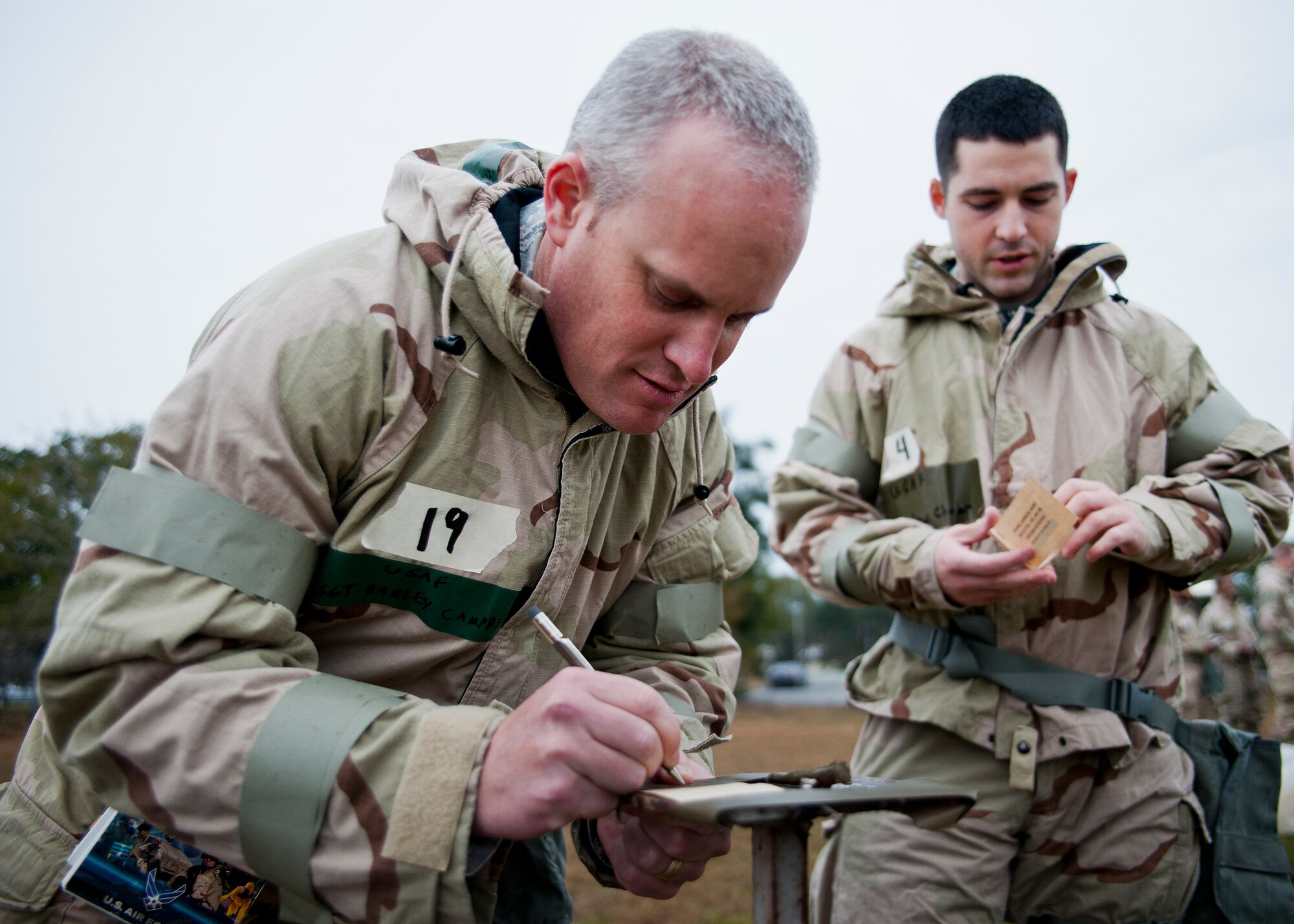 An Airman makes a note below the M8 contamination paper during a rainy Phase II readiness exercise Feb. 4 at Eglin Air Force Base, Fla.  A Phase II evaluates an Airman’s ability to meet wartime and contingency taskings of employing and sustaining the force and the ability to survive and operate. More than 30 potential deployers received classroom and practical field training during the exercise. (U.S. Air Force photo/Samuel King Jr.)