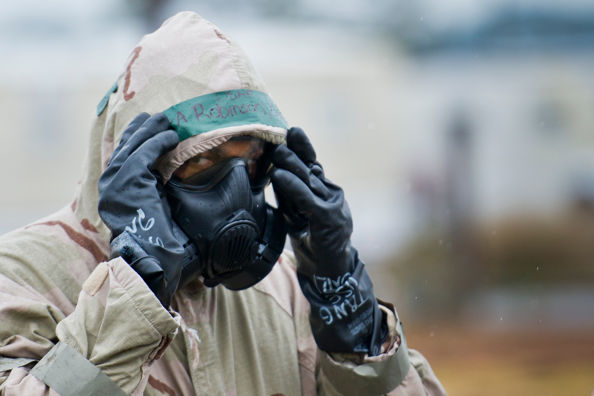 An Airman adjusts his hood and gas mask during a rainy Phase II readiness exercise Feb. 4 at Eglin Air Force Base, Fla.  A Phase II evaluates an Airman’s ability to meet wartime and contingency taskings of employing and sustaining the force and the ability to survive and operate. More than 30 potential deployers received classroom and practical field training during the exercise. (U.S. Air Force photo/Samuel King Jr.)