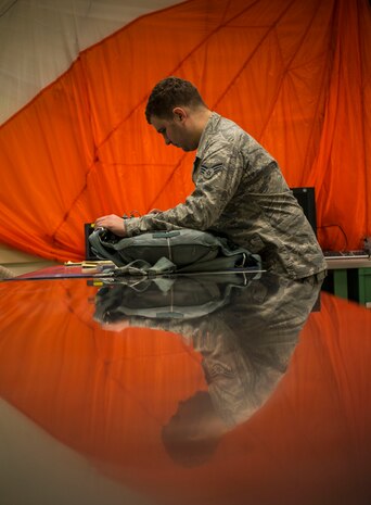 Senior Airman Justin Turner, 437th Operations Support Squadron Aircrew Flight Equipment technician, inspects a parachute before storing it for future use Feb. 9, 2015, at Joint Base Charleston, S.C. AFE works through the night to provide aircrew members with safe and reliable equipment, including night vision goggles, helmets, masks and even parachutes. (U.S. Air Force photo/ Senior Airman Dennis Sloan)