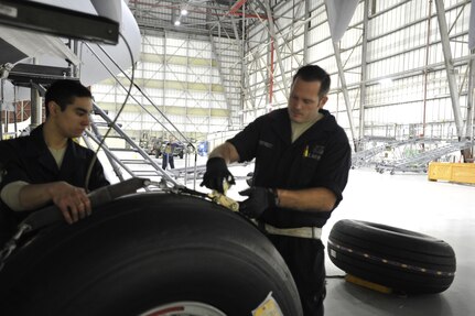 Airman 1st Class Andrew Palmer (left) and Staff Sgt. Michael Overstreet, crew chiefs with the 437th Maintenance Squadron, install tire number two during a home inspection check (HSC) during night shift at Joint Base Charleston, S.C., Feb. 9, 2015. The HSC hanger upgraded their light fixtures recently to LEDs in order to have maximum lighting for inspections. (U.S. Air Force photo/Tech. Sgt. Renae Pittman)