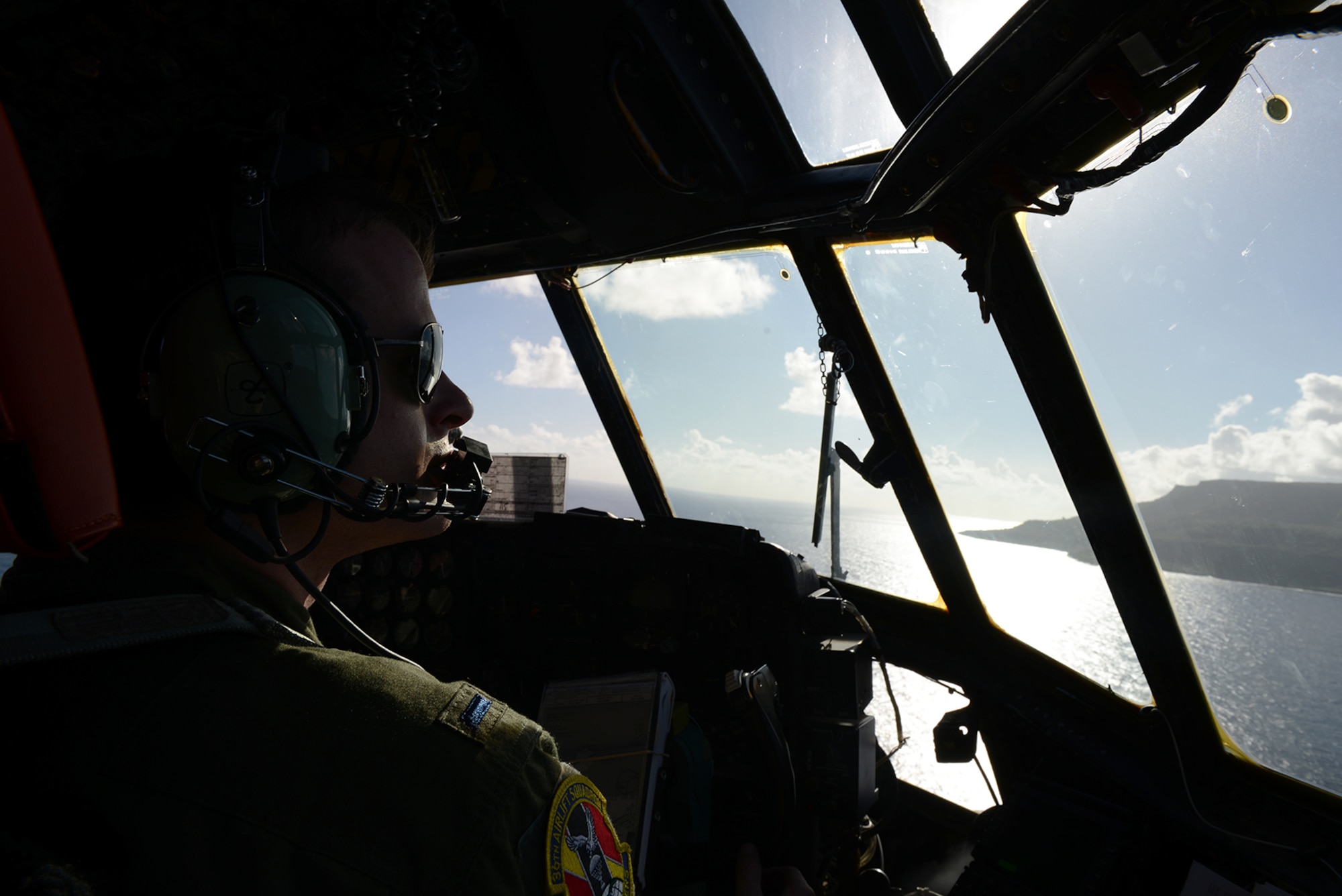1st Lt. Joshua Drapes, 36th Airlift Squadron co-pilot, looks out towards the Marianas islands Jan. 29, 2015. A crew from the 36 AS supported a mission to Tinian in preparations for Cope North 2015. (U.S. Air Force photo by Senior Airman Desiree Economides/Released)
