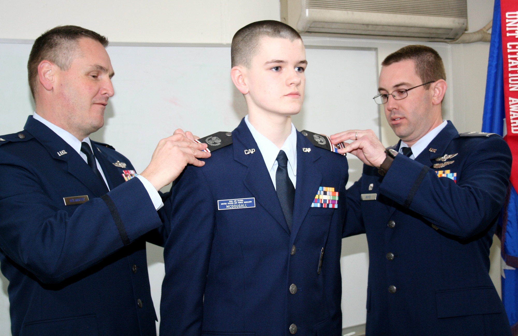 Col. Douglas DeLaMater (left), 374th Airlift Wing commander, and Civil Air Patrol Lt. Col. Adam Boyd, Yokota Cadet Squadron commander, pin Cadet Capt. Michael McDougall, NHQ-103 Cadet Squadron commander, at Yokota Air Base, Japan, Feb. 6, 2015. Roughly five percent of those who enter the CAP cadet program reach the rank of Cadet Captain. (Civil Air Patrol photo by 2Lt Billie Thompson/Released)