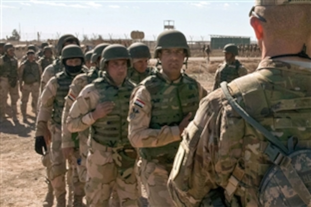 U.S. Army Command Sgt. Maj. Michael A. Grinston, foreground right, reviews Iraqi army trainees passing by to observe a platoon live-fire demonstration on Camp Taji, Iraq, Feb, 5, 2015. Grinston is the senior enlisted advisor to the 1st Infantry Division. In an upcoming session, Iraqis will lead a similar live-fire exercise requiring the use of complex maneuver and communication among units.