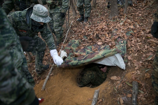 U.S. Marine Lance Cpl. Daniel S. Adams, a Tulsa, Oklahoma, native, sits in a hiding position dug by Republic of Korea and U.S. Marines during Korean Marine Exchange Program 15-4 Feb. 4 at the Pyeongchang Winter Training Facility, Pyeongchang, Republic of Korea. The ROK and U.S. Marines learned different ways to survive in the cold mountainous terrain and also new ways of concealing themselves. This exercise underlines the enduring alliance and friendship between the ROK and U.S. Adams is a rifleman with Company L, 3rd Battalion, 3rd Marine Regiment, currently assigned to 4th Marine Regiment, 3rd Marine Division, III Marine Expeditionary Force under the unit deployment program. The ROK Marines are with 1st Reconnaissance Battalion, 1st ROK Marine Division. 