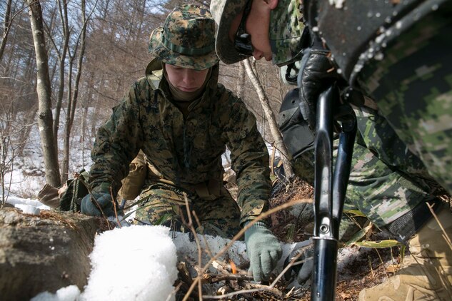 U.S. Marine Cpl. Matthew G. Nolan, center, tends to a fire alongside Republic of Korea Marine Staff Sgt. Kim Yung Hwa during Korean Marine Exchange Program 15-4 Feb. 4 at the Pyeongchang Winter Training Facility, Pyeongchang, Republic of Korea. Survival skills such as knowing how to find food and clean water and how to build fires and shelters are essential skills in nearly every environment, so this training allows the Marines to be more proficient at what they do, according to U.S. Marine Sgt. Joseph K. Blankenship. The overarching goal of KMEP is to enhance and improve the interoperability of ROK and U.S. Marine Corps forces. Nolan, a Seattle, Washington,native, is a rifleman with Company L, 3rd Battalion, 3rd Marine Regiment, currently assigned to 4th Marine Regiment, 3rd Marine Division, III Marine Expeditionary Force under the unit deployment program. Kim, a Kyeong Kido, ROK, native, is a reconnaissance man with 1st Reconnaissance Battalion, 1st ROK Marine Division. 