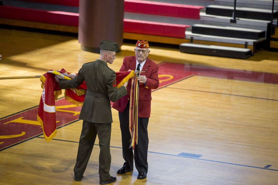 A member of the Second Marine Division Association attaches a battle streamer to the 2nd Marine Division’s colors during a battle colors rededication ceremony aboard Camp Lejeune, N.C., Jan. 30, 2015. Cpl. Trevor Wallace, left, assisted in attaching the Marine Corps Expeditionary Streamer with one Bronze Star. Marines from past and present joined together during the ceremony to celebrate the future as well as remembering their roots. (U.S. Marine Corps photo by Pfc. Dalton Precht/Released)