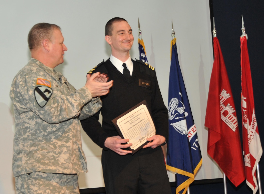 During the Jan. 23 Town Hall, Huntsville Center Commander Col. Robert J. Ruch presents Lt. Cdr. Brandon Groh with a Certificate of Achievement on behalf of Brig. Gen. Jeffrey Clark, Director of the Walter Reed National Military Medical Center.