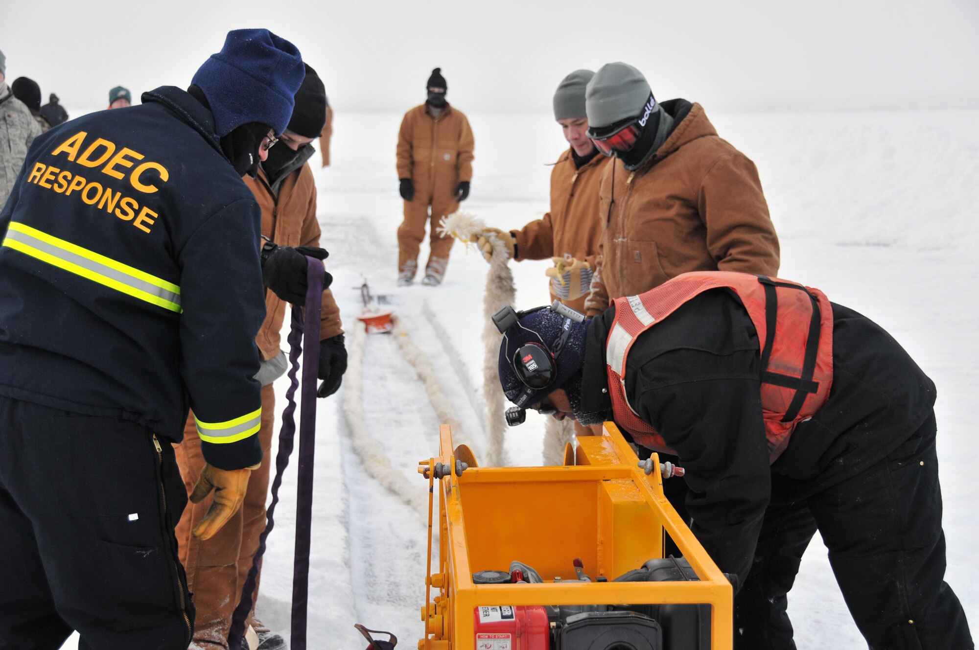 Members of the Alaska Department of Environmental Conservation, 611th Civil Engineer Squadron, and U.S. Navy Supervisor of Salvage and Diving set up the rope mop skimmer during an Arctic oil spill response exercise Feb. 4. A trench is dug a certain depth in the ice and holes are drilled to allow the oil/product to rise up into the trench to be collected. The skimmer rotates through the trench collecting the oil and sends it to a holding tank. The units participated in the exercise to learn Arctic spill response tactics and techniques. (U.S. Air Force photo/Tech. Sgt. John Gordinier)