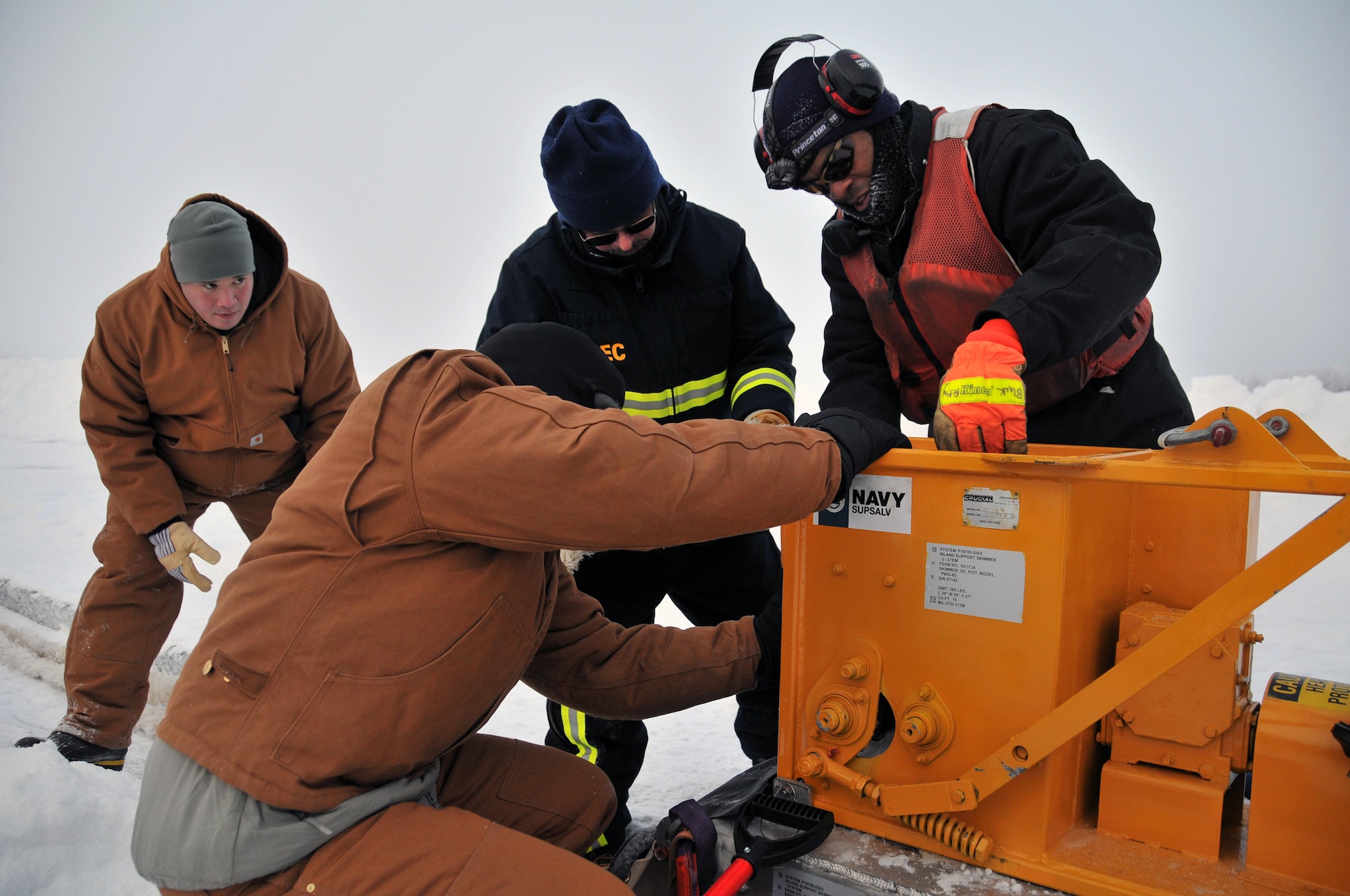 Members of the Alaska Department of Environmental Conservation, 611th Civil Engineer Squadron, and U.S. Navy Supervisor of Salvage and Diving set up the rope mop skimmer during an Arctic oil spill response exercise Feb. 4, 2015, in Alaska. A trench is dug a certain depth in the ice and holes are drilled to allow the oil/product to rise up into the trench to be collected. The skimmer rotates through the trench collecting the oil and sends it to a holding tank. The units participated in the exercise to learn Arctic spill response tactics and techniques. (U.S. Air Force photo/Tech. Sgt. John Gordinier)