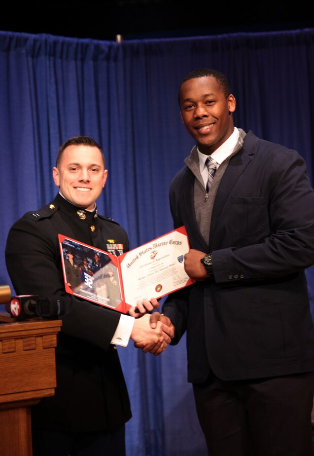 BUFFALO, NY – Canisius High School Crusaders tight end T. J. Wheatley receives a certificate of appreciation from Marine Capt. Michael A. Kelly during a signing ceremony at his high school, Feb. 4. Wheatley received the certificate signed by Maj. Gen. Mark Brilakis for playing in the Semper Fidelis All American Bowl this year. Wheatley just signed to play for Michigan State, his father former NFL running back Tyrone Wheatley’s Alma Mata, next year. Brilakis is the commanding general of Marine Corps Recruiting Command. Kelly is the operations officer for Marine Corps Recruiting Station Buffalo. (Official U.S. Marine Corps photo by Sgt. Christopher O’Quin/Released)