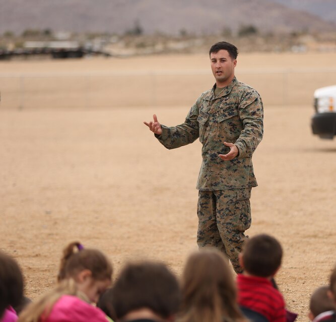 Sgt. Darren Westmoreland, military working dog handler, K-9 Unit, Provost Marshal’s Office, answers a question from a Joshua Tree Elementary School student about the Marine’s job as a MWD handler during a demonstration at the school, Jan. 29, 2015. The MWD handlers answered questions that students and teachers had about the MWDs. (Official Marine Corps Photo by Lance Cpl. Julio McGraw/Released)