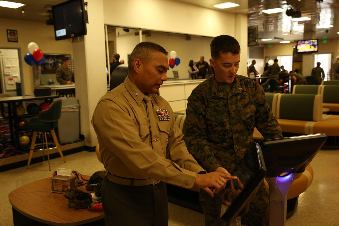 Lt. Col. Frank Marilao, assistant chief of staff, Marine Corps Community Services, shows Cpl. Anthony Gackle, motor transportation operator, Marine Wing Support Squadron 374, how to share his bowling experience by logging onto Facebook from the bowling alley during the Grand Re-Opening and 35th Anniversary Celebration at the Sandy Hills Bowling Center, Jan. 29, 2015. (Official Marine Corps Photo by Lance Cpl. Olivia Day/Released)