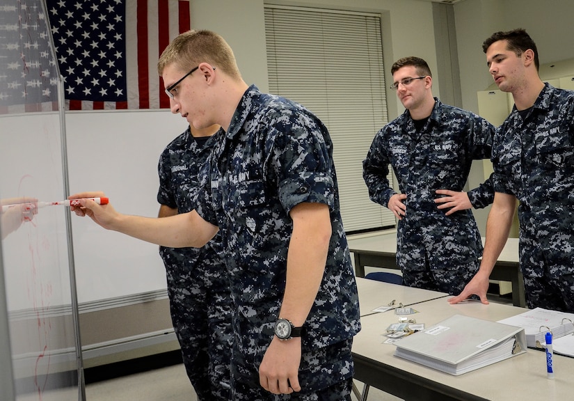 Naval Nuclear Power Training Command students study well into the night using a dry erase board to solve equations and prepare for their next exam Feb. 9, 2015, at Joint Base Charleston Weapons Station. NNPTC classrooms remain open until midnight, so students can study any part of the curriculum. Instructors also stay after hours to work with Sailors individually, which is not always possible during a typical school day.  (U.S. Air Force photo/ Senior Airman Dennis Sloan)
