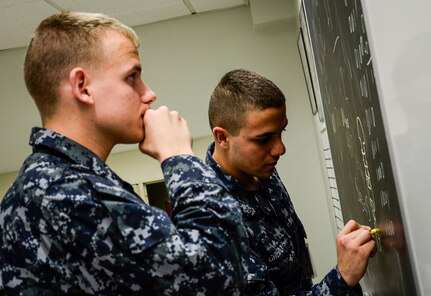 Naval Nuclear Power Training Command students study well into the night using a chalk board to solve equations and prepare for their next exam Feb. 9, 2015, at Joint Base Charleston – Weapons Station. NNPTC classrooms remain open until midnight, so students can study any part of the curriculum. Instructors also stay after hours to work with Sailors individually, which is not always possible during a typical school day. (U.S. Air Force photo/ Senior Airman Dennis Sloan)