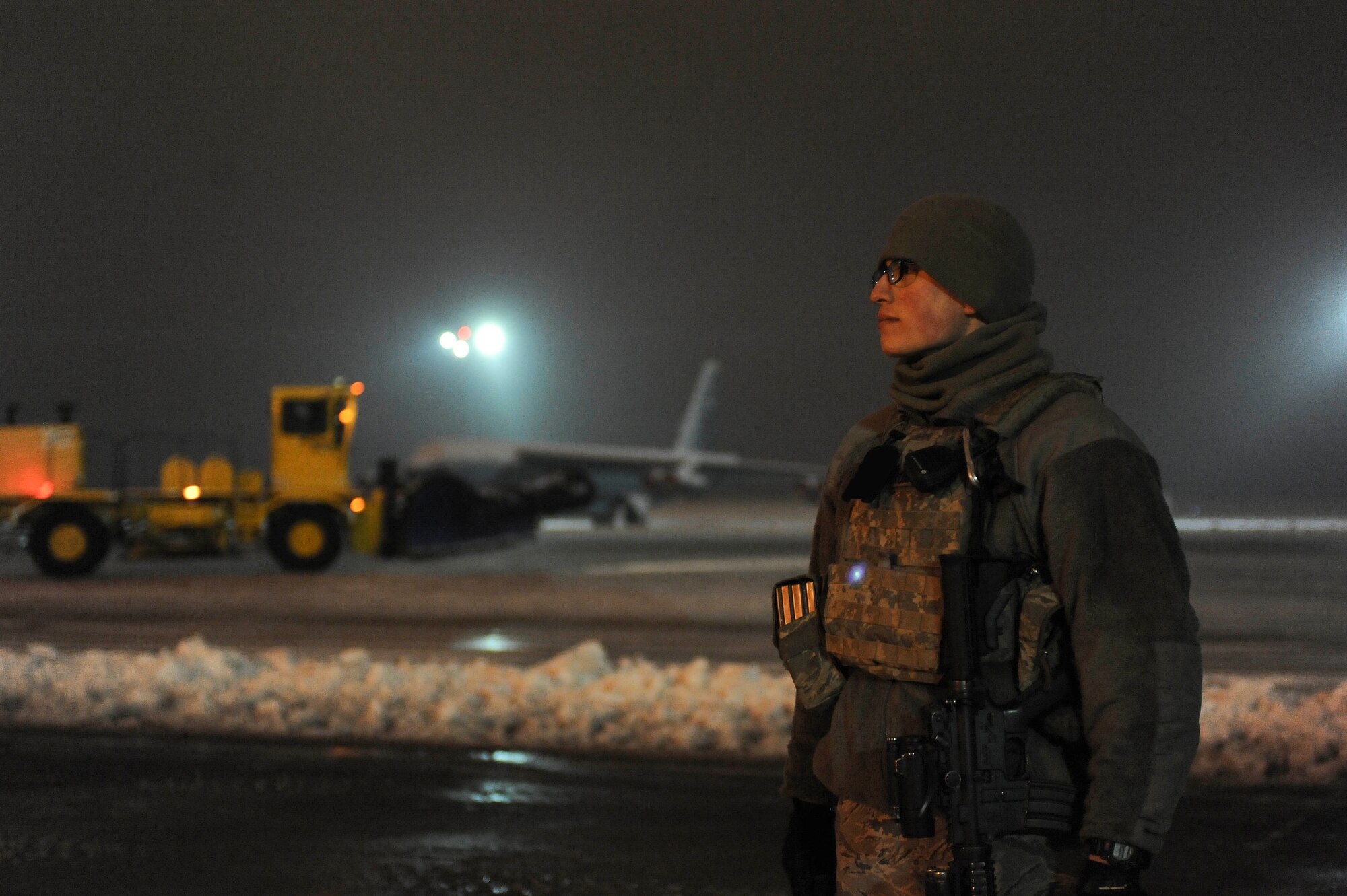 Senior Airman Sergio Romo, 5th Security Forces Squadron law enforcement patrolman, patrols the flightline as snow plows pass behind him on Minot Air Force Base, N.D., Jan. 24, 2015. Romo works a 12-hour shift during the night and usually ends his day at 7 a.m. (U.S. Air Force photo/Senior Airman Stephanie Morris)
