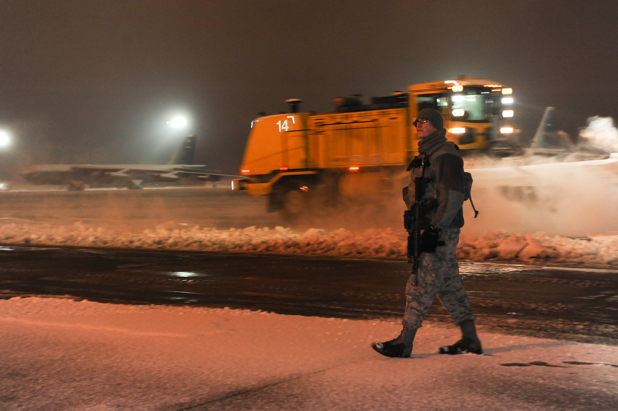Senior Airman Sergio Romo, 5th Security Forces Squadron law enforcement patrolman, patrols the flightline as snow plows pass behind him on Minot Air Force Base, N.D., Jan. 24, 2015. Romo works a 12-hour shift during the night and usually ends his day at 7 a.m. (U.S. Air Force photo/Senior Airman Stephanie Morris)
