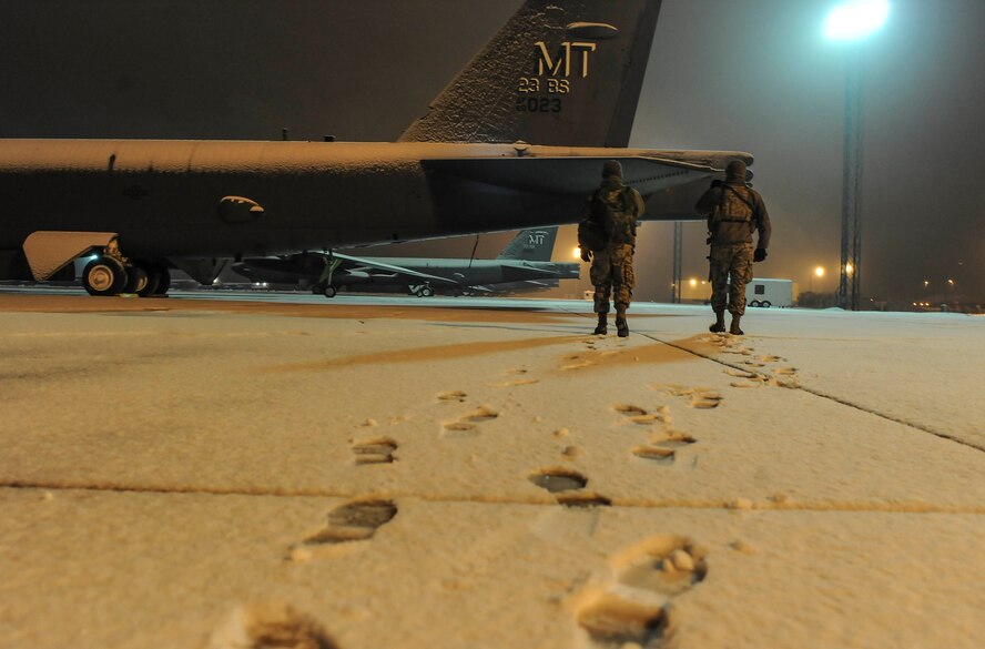 (left) Airman 1st Class Zane Crady, 5th Security Forces Squadron response force team member, and (right) Senior Airman Sergio Romo, 5th SFS law enforcement patrolman, walk towards a B-52H Stratofortress on Minot Air Force Base, N.D., Jan. 24, 2015. Romo and Crady patrolled the flightline overnight searching for any suspicious activity. (U.S. Air Force photo/Senior Airman Stephanie Morris)