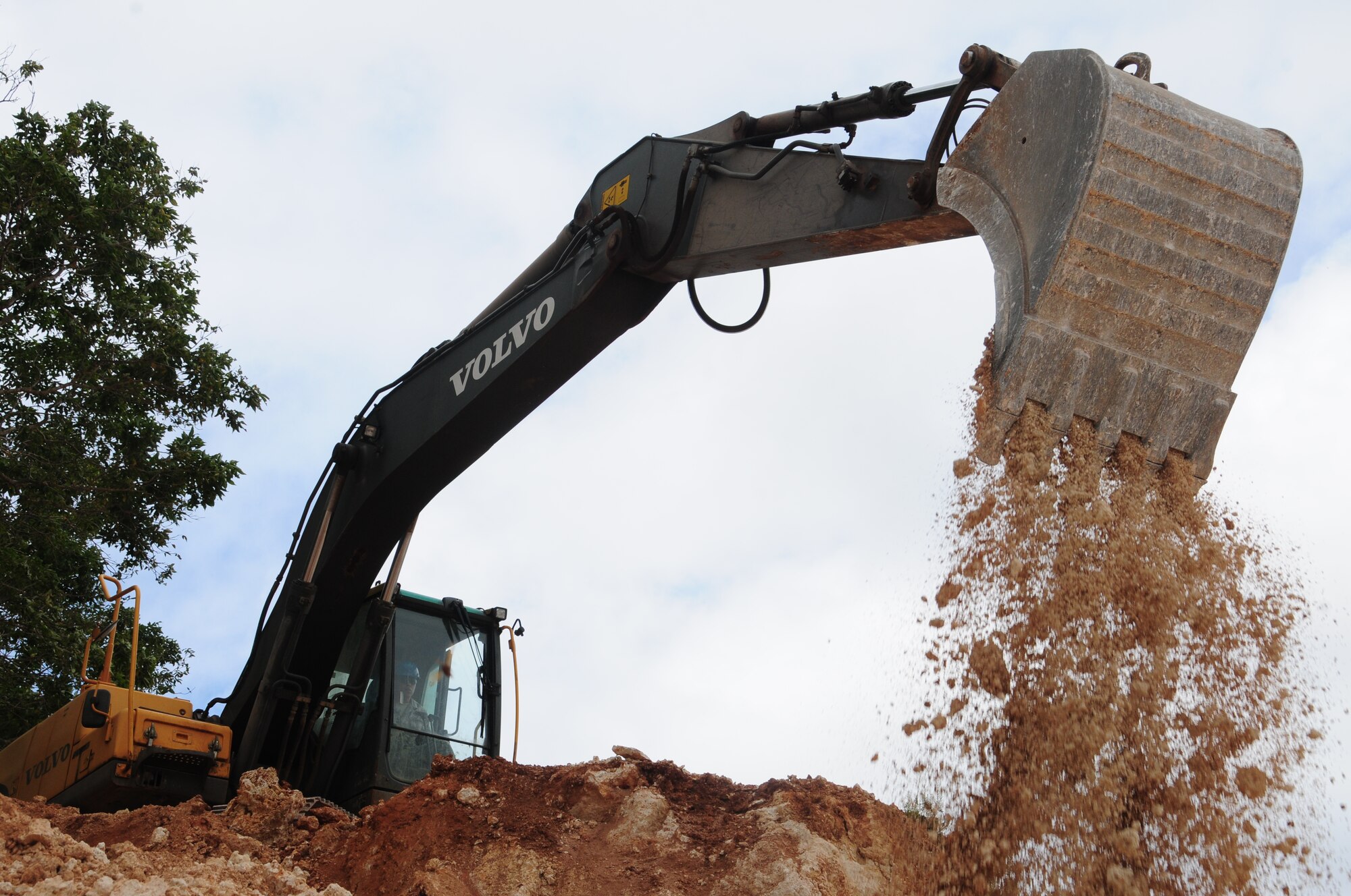 U.S. Air National Guard Airman 1st Class Christian Flores with the 146th Airlift Wing Civil Engineering Squadron moves dirt to complete a mission at the 554th Red Horse Squadron, Andersen AFB Guam on February 4, 2015. (U.S. Air National Guard photo by Airman 1st Class Madeleine Richards/Released)