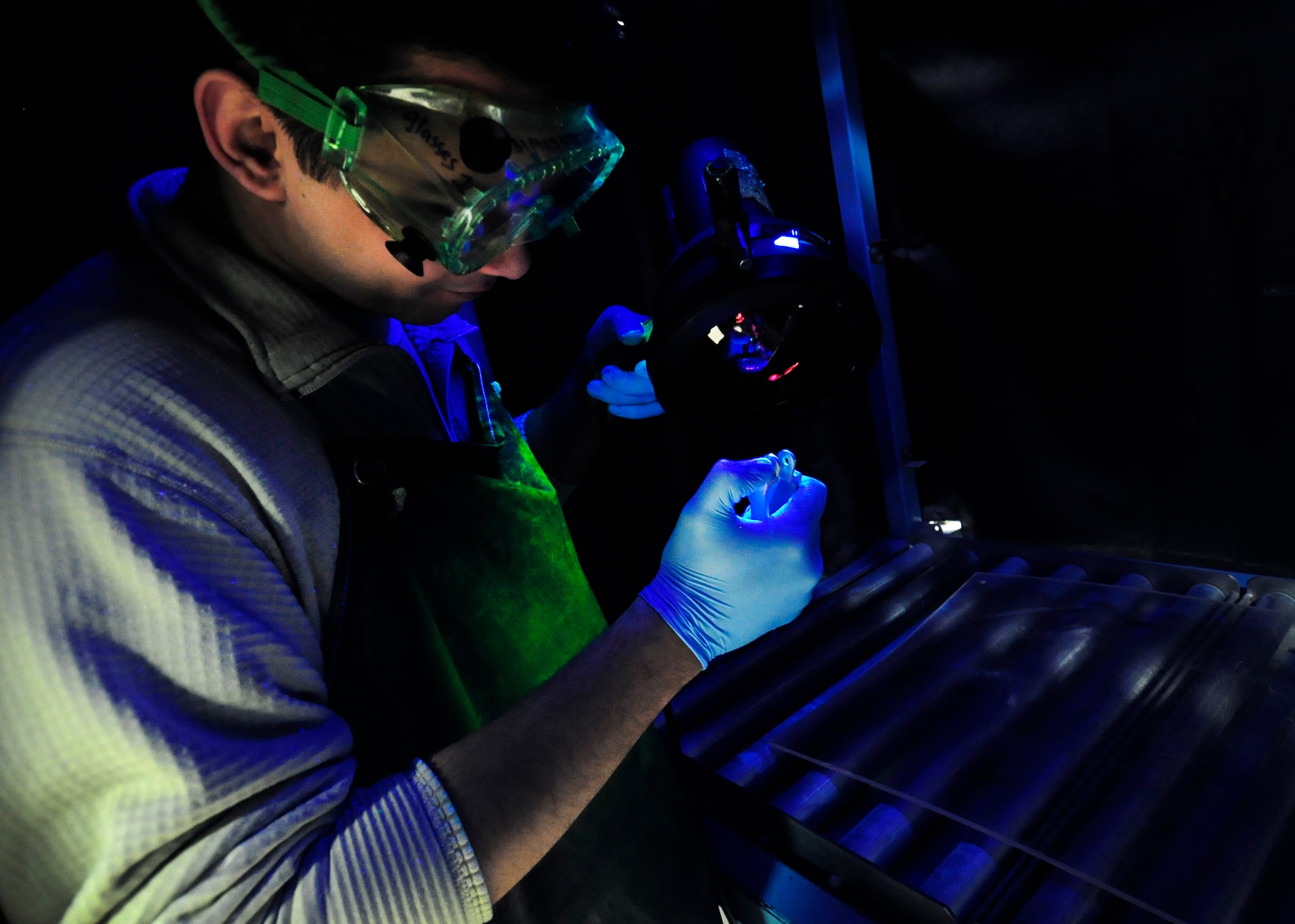 U.S. Air Force Senior Airman Jon Zengotita, 31st Maintenance Squadron non-destruction inspection journeyman, inspects an F-16 Fighting Falcon ejection seat handle for cracks, Feb. 10, 2015, at Aviano Air Base, Italy. After fluorescent oil is poured on a part, it attaches to any cracks and can be seen when a magnetic field is placed on either end of the part. This method allows Airmen to inspect parts without destroying or damaging a product or material. NDI is responsible for testing the integrity of aircraft parts before they become a potential hazard.  (U.S. Air Force photo by Airman 1st Class Deana Heitzman/Released