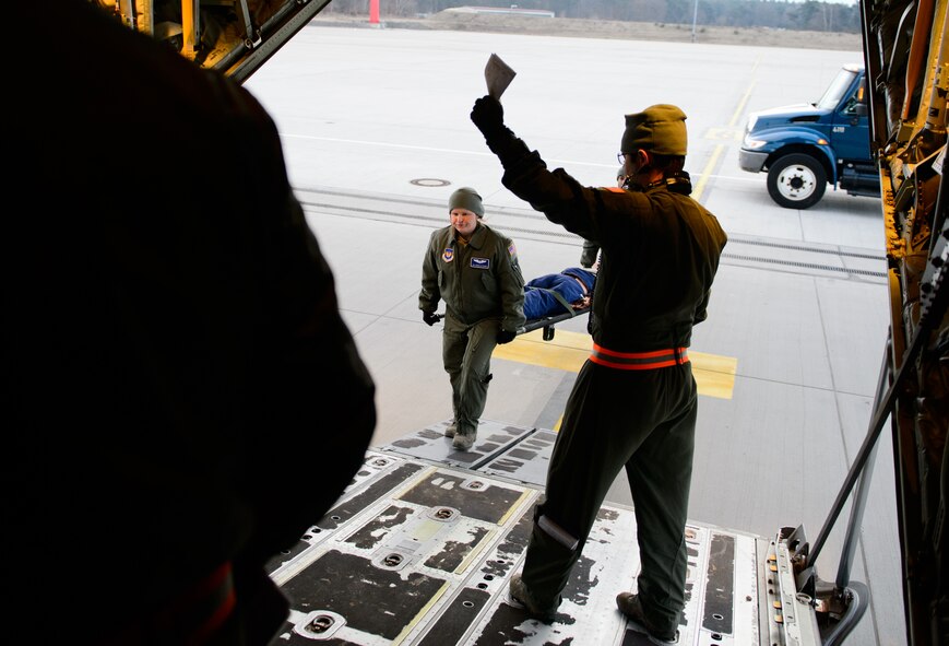 Senior Airman Michelle Burns, 86th Aeromedical Evacuation Squadron ground team member, middle, loads a mannequin during a training sortie at Ramstein Air Base, Germany, Feb. 6, 2015. Burns, as a ground team member, augments the crew flying each day to improve the process of setting up aircraft for aeromedical evacuations. (U.S. Air Force photo/Senior Airman Armando A. Schwier-Morales)