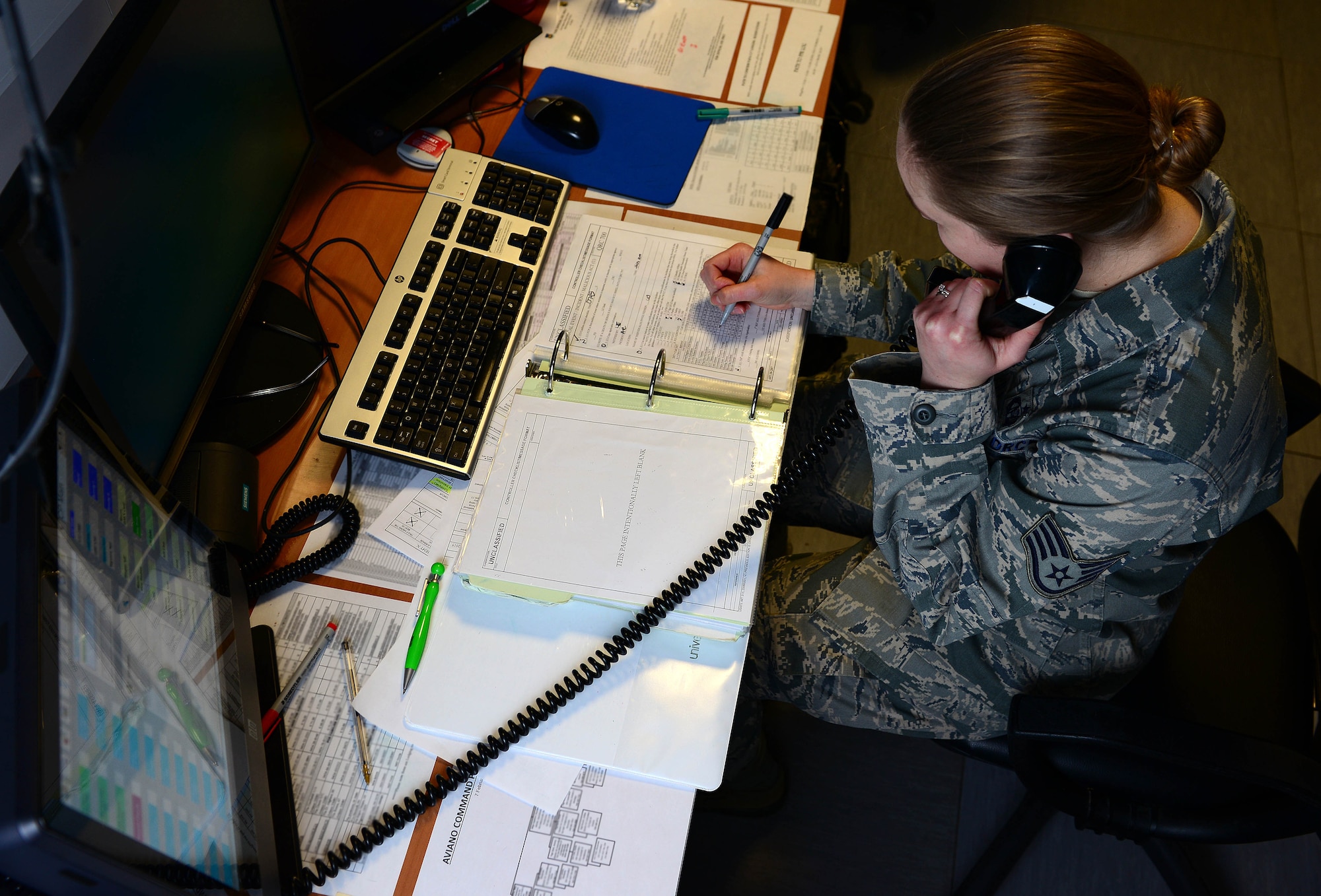 U.S. Air Force Staff Sgt. Lynn Fuhrmeister, 31st Fighter Wing Command Post emergency actions controller, receives an off-base phone call, Feb. 9, 2015, at Aviano Air Base, Italy. The 26-manned office communicates to leadership daily with messages received from higher headquarters command posts, such as U.S. Air Forces in Europe and Air Forces Africa and the Pentagon. (U.S. Air Force photo by Senior Airman Matthew Lotz/Released)