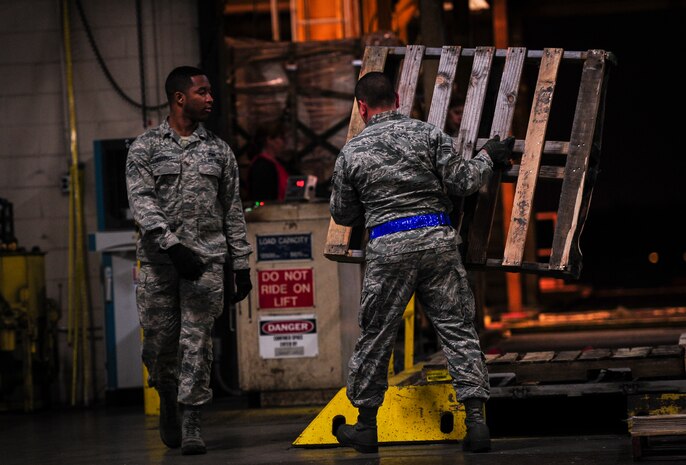 Senior Airman Melissa Howerton and Senior Airmen Darwin Polo, 437th Aerial Port Squadron air transportation specialists, prepare to cover a pallet with a protective sheet Feb. 9, 2015, at Joint Base Charleston, S.C. The need for safe, precise, reliable airlift never stops, and therefore neither do the “Port Dawgs.” They work through the night to process cargo and load it on and off Charleston’s fleet of C-17 Globemaster IIIs.(U.S. Air Force/Airman 1st Class Clayton Cupit)
