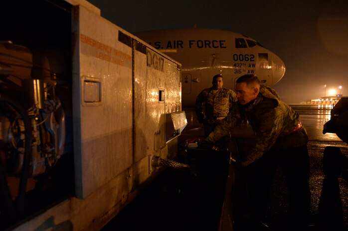 Staff Sgt. Gregory House, a quality assurance inspector with the 437th Maintenance Group, looks on as Staff Sgt. Timothy Womble, an aerospace ground equipment technician with the 437th Maintenance Squadron, refuels a generator during a rainy night at Joint Base Charleston, S.C., Feb. 9, 2015. Many units assigned to the 437th Airlift Wing work around the clock, no matter the weather, to ensure the mission gets done. (U.S. Air Force photo/Tech. Sgt. Renae Pittman)