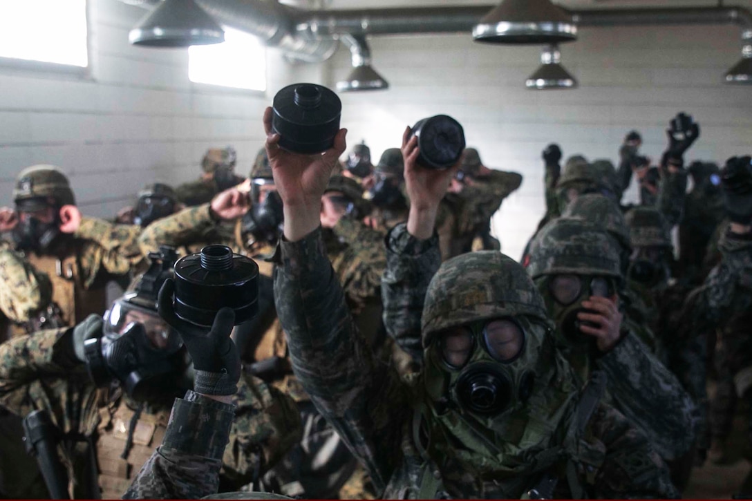 South Korean and U.S. Marines break the seal of their gas masks during the Korean Marine Exchange Program 15-17 on the Cham Sae Mi Close-Quarters Battle Training Facility in Pohang, South Korea, Feb. 9, 2015. Breaking the seal allows the Marines to be exposed to the chemical agent in the air. 