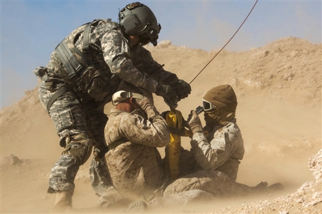 A U.S. soldier secures Marines to a cable dangling from a UH-60 Black Hawk medevac helicopter during a casualty evacuation exercise near Camp Buehring, Kuwait, Feb. 5, 2015. The soldiers are flight medics assigned to Company C, 2nd Battalion, 3rd Aviation Regiment, while the Marines and sailors are assigned to the 24th Marine Expeditionary Unit.