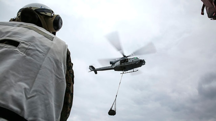 A landing support specialist watches as a UH-1Y Huey attached to Marine Medium Tiltrotor Squadron 262, 31st Marine Expeditionary Unit, flies away with a load of tires during a helicopter support team exercise Feb. 6 on the flight deck of the USS Bonhomme Richard. This was the first time the Marines executed an HST exercise aboard a ship. The Marines are with Combat Logistics Battalion 31, 31st MEU, and are currently deployed in support of the annually-scheduled Spring Patrol of the Asia-Pacific region.
