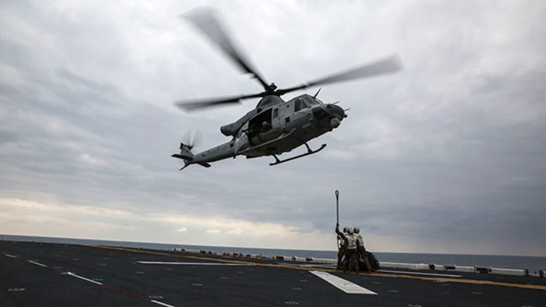 Landing support specialists wait for a UH-1Y Huey attached to Marine Medium Tiltrotor Squadron 262, 31st Marine Expeditionary Unit, to lower itself so they can hook on a load of tires during a helicopter support team exercise Feb. 6 on the flight deck of the USS Bonhomme Richard. Using a MK-105 cable, also known as the Q-tip, the Marines hooked the load onto the bottom of the Huey. The Marines are with Combat Logistics Battalion 31, 31st MEU, and are currently deployed in support of the annually-scheduled Spring Patrol of the Asia-Pacific region.