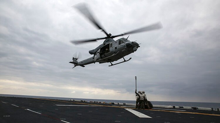 Landing support specialists wait for a UH-1Y Huey attached to Marine Medium Tiltrotor Squadron 262, 31st Marine Expeditionary Unit, to lower itself so they can hook on a load of tires during a helicopter support team exercise Feb. 6 on the flight deck of the USS Bonhomme Richard. Using a MK-105 cable, also known as the Q-tip, the Marines hooked the load onto the bottom of the Huey. The Marines are with Combat Logistics Battalion 31, 31st MEU, and are currently deployed in support of the annually-scheduled Spring Patrol of the Asia-Pacific region.