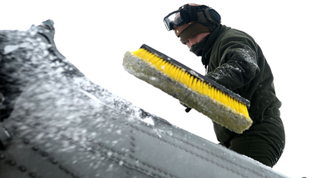 Lance Cpl. Nicholas Chieu, a crew chief with Marine Heavy Helicopter Squadron 464, brushes snow and ice off of a CH-53 Super Stallion during a deployment for training exercise aboard Camp Dawson, West Virginia, Jan. 30, 2015. Inclement weather caused the Marines to take extra steps in preparing the helicopters for flight.