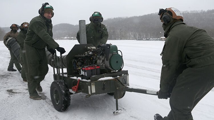 Marines with Marine Heavy Helicopter Squadron 464 transport a preheater to a CH-53 Super Stallion to warm up the engines before powering them up during the squadron’s deployment for training exercise aboard Camp Dawson, West Virginia, Jan. 30, 2015. The squadron battled heavy snowfall during the beginning of their exercise, and they took the proper precautions to counteract the inclement weather.