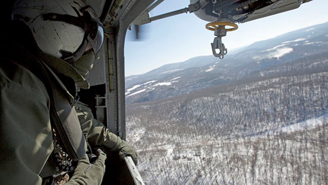 Corporal Adam Lindsey, a crew chief with Marine Heavy Helicopter Squadron 464, looks out of a window on a CH-53 Super Stallion during a confined area landing flight as part of the squadron’s deployment for training exercise aboard Camp Dawson, West Virginia., Jan. 31, 2015. The goal of the DFT is to prepare the squadron to work and effectively accomplish their mission in a different environment than they are used to.
