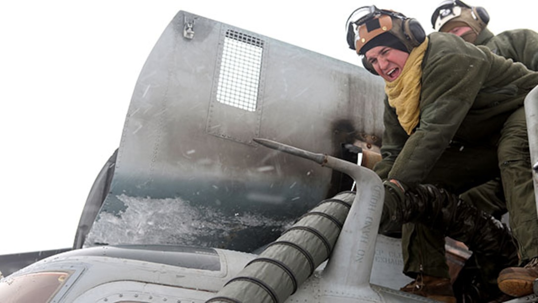 Staff Sgt. Justin Hussey, a helicopter airframe mechanic with Marine Heavy Helicopter Squadron 464, runs a hose from a preheater to one of the engines on a CH-53 Super Stallion during a deployment for training exercise aboard Camp Dawson, West Virginia, Jan. 30, 2015. The squadron used preheaters to warm up the helicopters because of the heavy snow and ice at Camp Dawson.