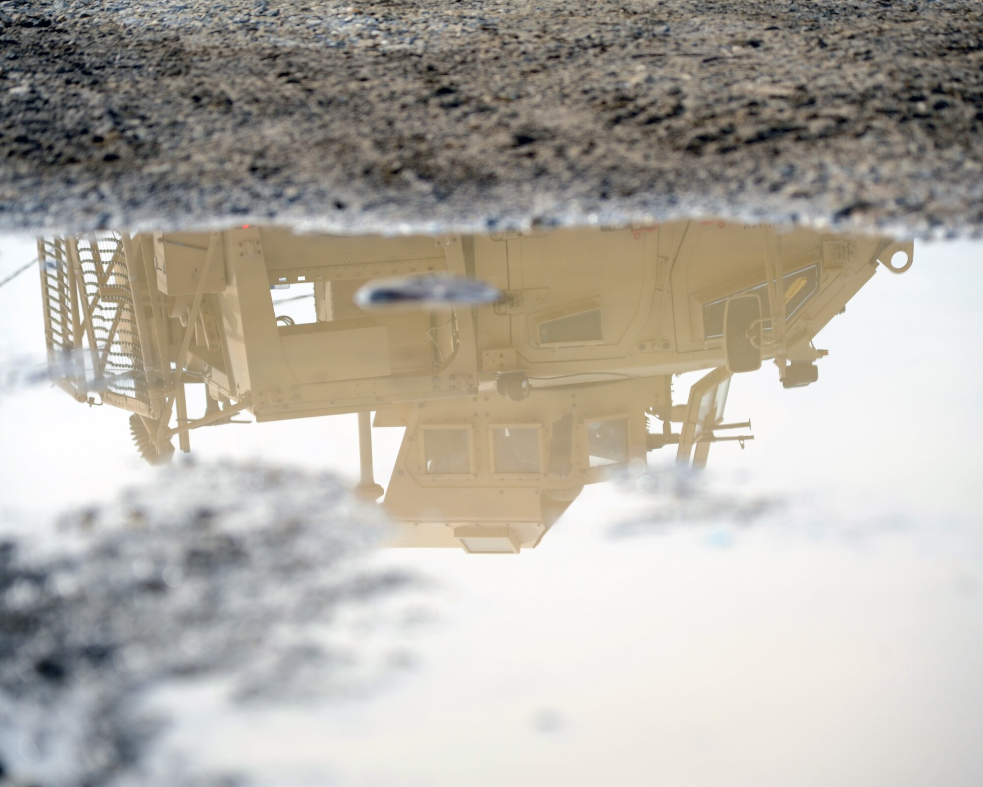 The reflection of an armored vehicle can be seen in a mud puddle during a combined-joint training exercise at Bagram Airfield, Afghanistan Feb. 6, 2015. U.S. and Georgian service members participated in the base-wide exercise enhancing their abilities to respond in the event of attacks on the base and mass casualty incidents.  (U.S. Air Force photo by Master Sgt. James Law/released)