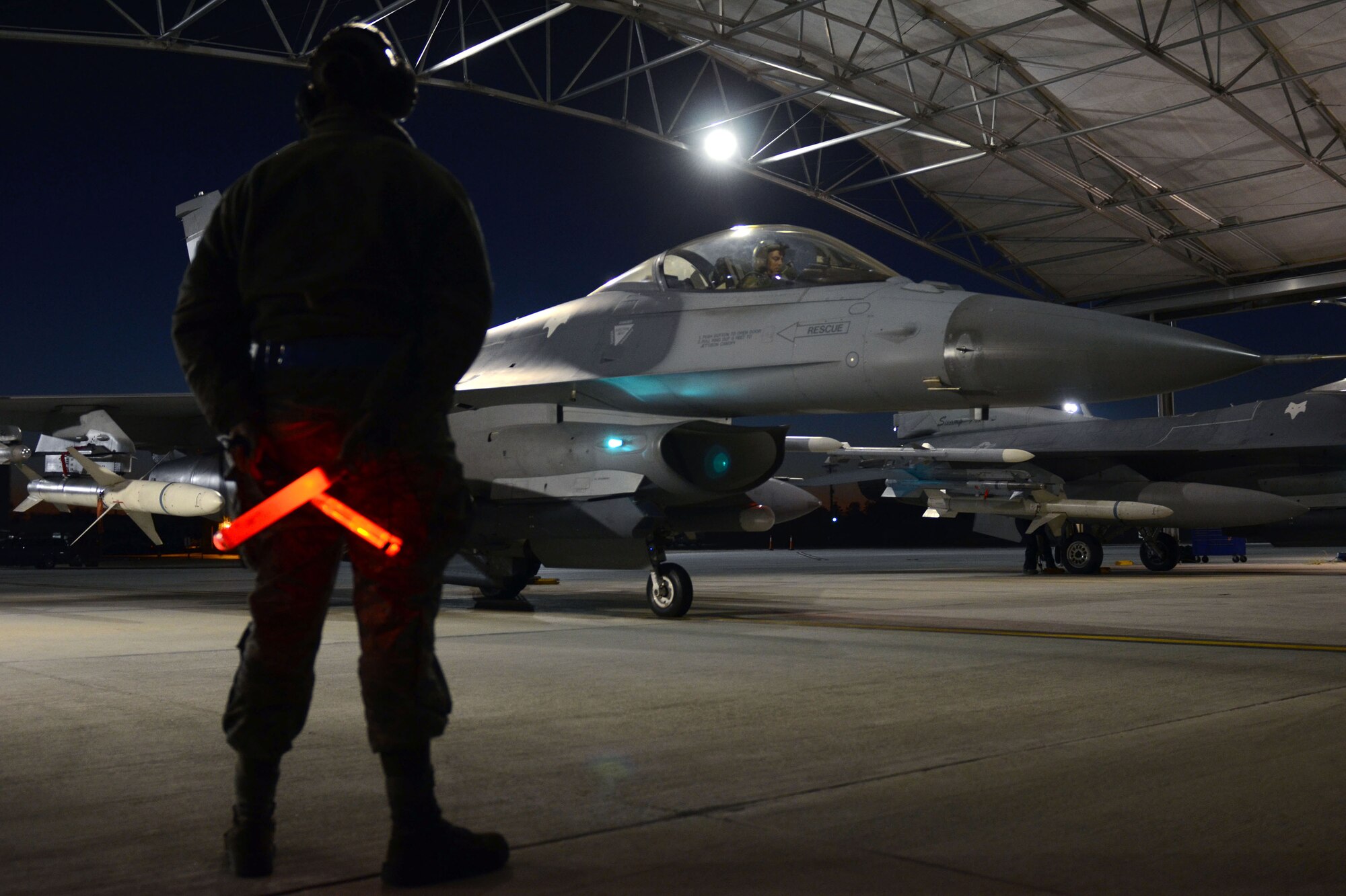 U.S. Air Force Airman 1st Class Jordan Mills, a crew chief with the 169th Aircraft Maintenance Squadron, waits as a pilot preforms pre-flight checks for his participation in the aviation surge at McEntire Joint National Guard Base, Feb. 7, 2015. The surge encompasses high tempo flying as part of vital training in preparation for deployments. (U.S. Air National Guard photo by Amn Megan Floyd/Released)