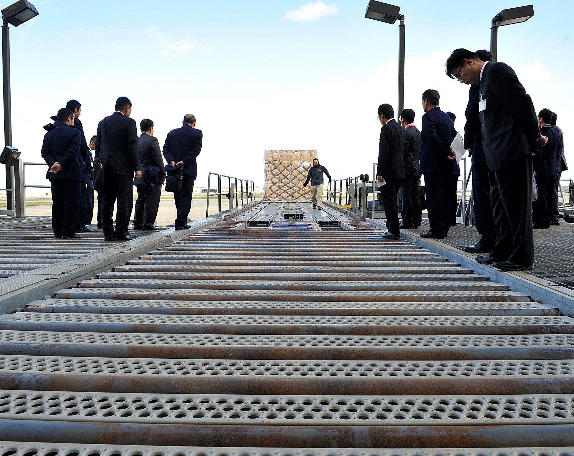 Takahiro Namizato (center), 733rd Air Mobility Squadron aircraft cargo truck operator, shows how to load cargo onto the Tunner 60k loader to Japan Air Self Defense Force members during their visit on Kadena Air Base, Okinawa, Japan, Feb. 10, 2015. The JASDF members had the opportunity to learn about how the 733rd Air Mobility Squadron's cargo system and also visited the 18th LRS supply facility and 18th Munitions Squadron. (U.S. Air Force photo by Naoto Anazawa)